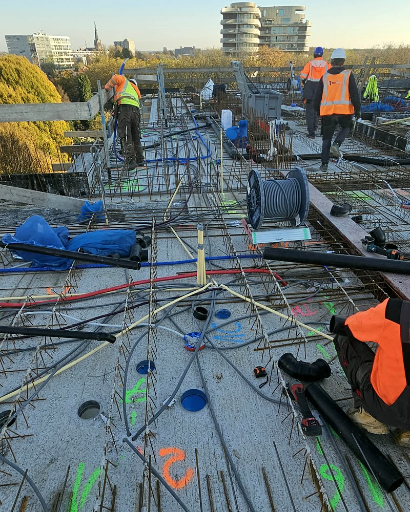 Elektriciens leggen leidingen in een betonvloer op de bouw